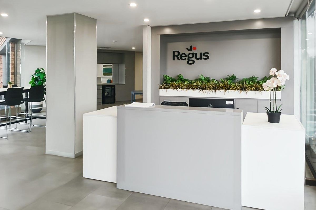 Modern office reception area featuring a clean, professional desk, recessed lighting, and neutral tiled flooring in a well-maintained corporate environment.