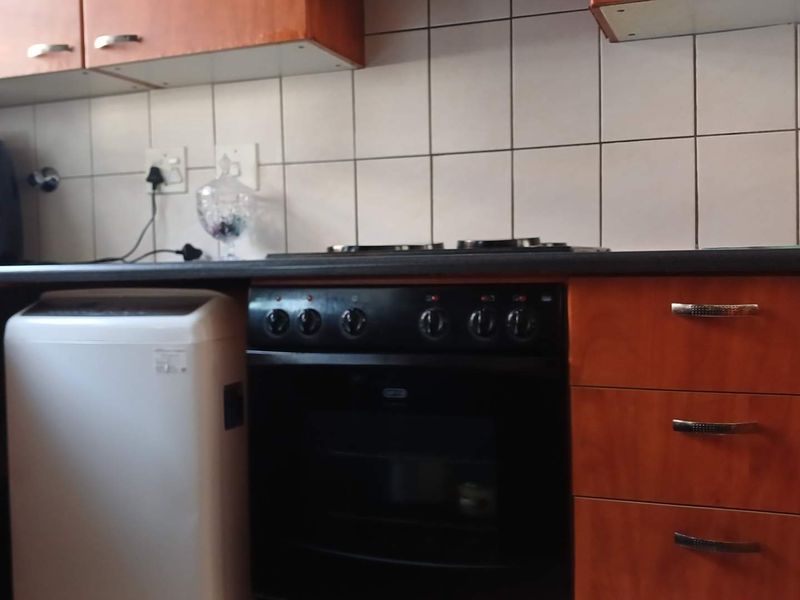 A functional kitchen area featuring wood-finish cabinetry, a tiled backsplash, and a built-in oven with a hob.