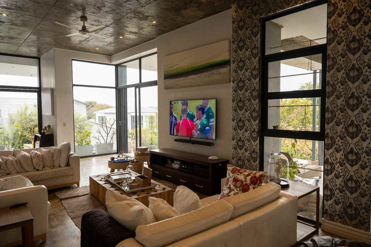 Spacious living room featuring high ceilings, large floor-to-ceiling windows, and modern finishes with access to an outdoor patio area.