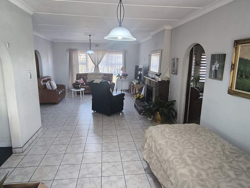 Spacious living room featuring neutral tiled flooring, a central fireplace, and classic archway transitions, offering a bright and functional layout.