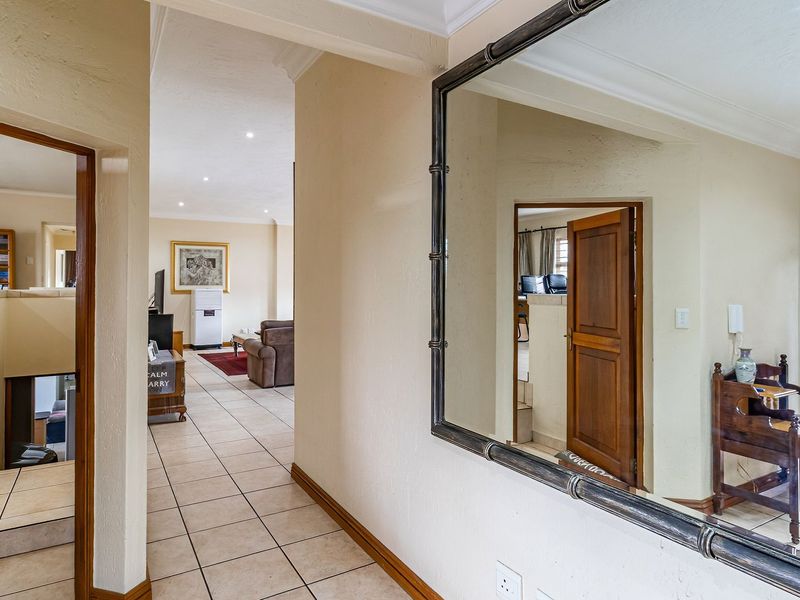 A bright, tiled hallway connecting multiple living areas, featuring neutral wall tones and classic architectural detailing.