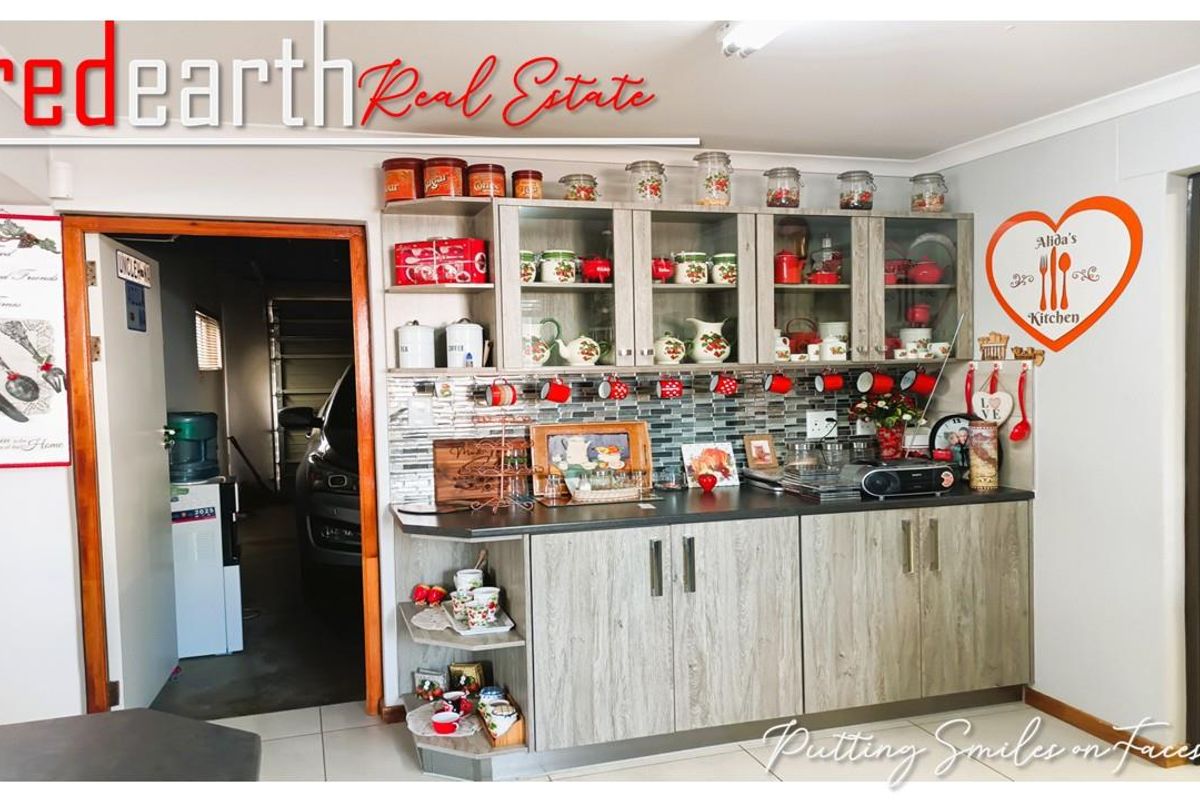 A functional kitchen area featuring wood-grain cabinetry, a mosaic tile backsplash, and dark laminate countertops, with an adjacent doorway leading to the garage.