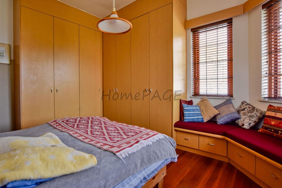 A bedroom featuring built-in wooden wardrobes and a custom corner window seat with integrated storage drawers.
