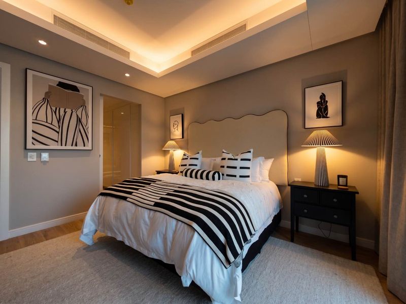 A modern, well-appointed bedroom featuring a recessed ceiling with integrated lighting, ducted air conditioning, and high-quality timber flooring.