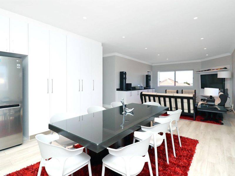 Spacious open-plan living and dining area featuring modern laminate flooring, recessed downlighting, and extensive built-in storage cabinetry.