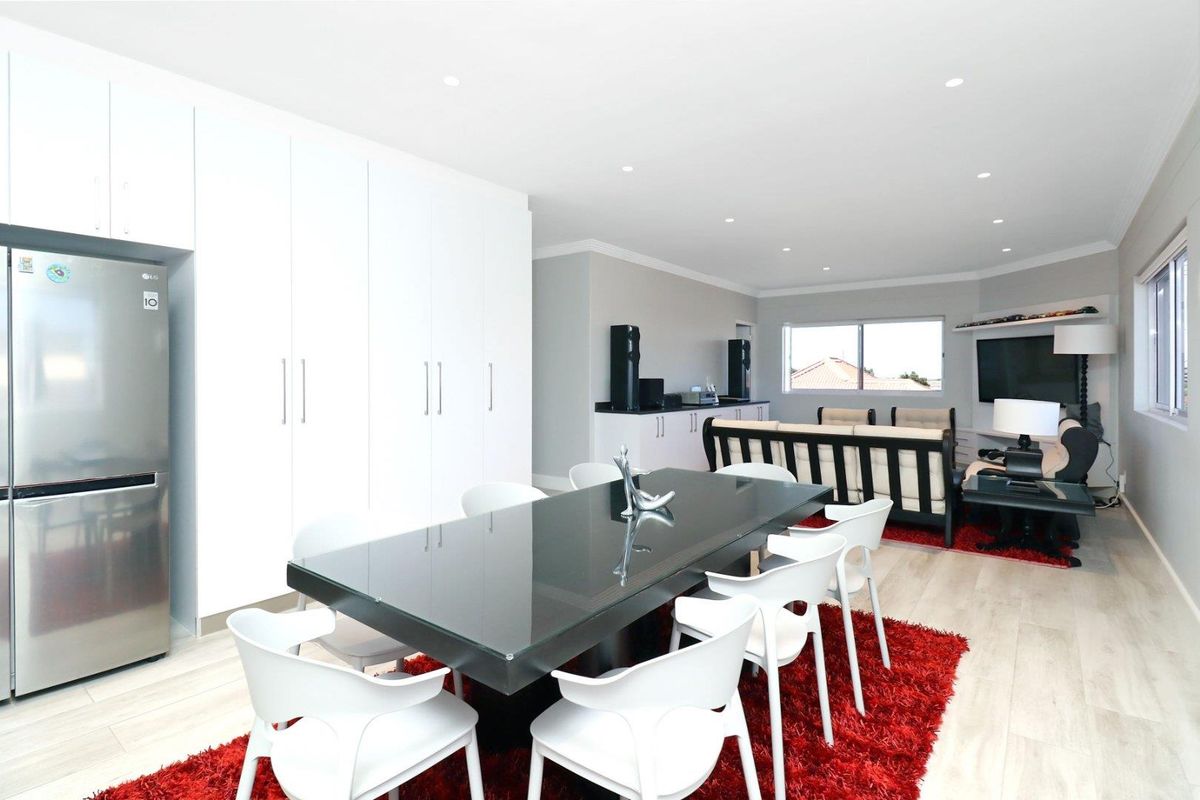 Spacious open-plan living and dining area featuring modern laminate flooring, recessed downlighting, and extensive built-in storage cabinetry.
