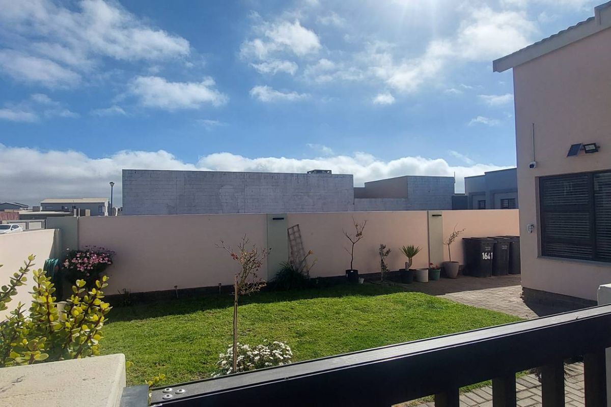 A private rear garden featuring a well-maintained lawn, paved pathway, and secure boundary walling, providing a functional outdoor space.