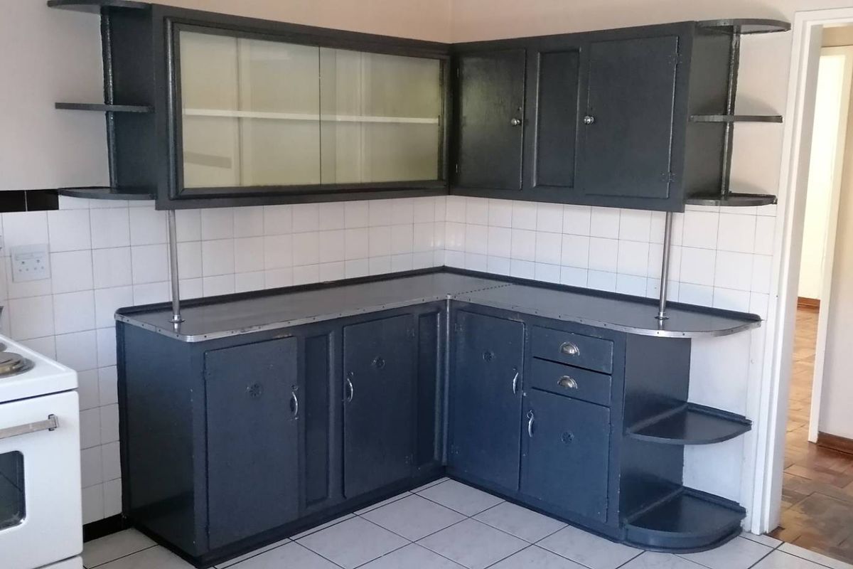 A dated kitchen featuring dark painted built-in cabinetry, tiled backsplash, and an electric stove, offering potential for a modern renovation.