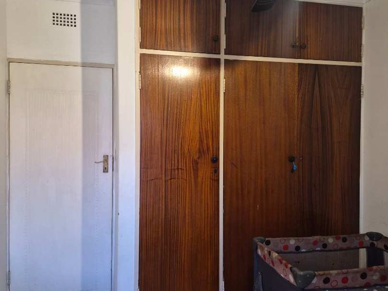 Bedroom featuring built-in wooden cupboards, a ceiling fan, and carpeted flooring.