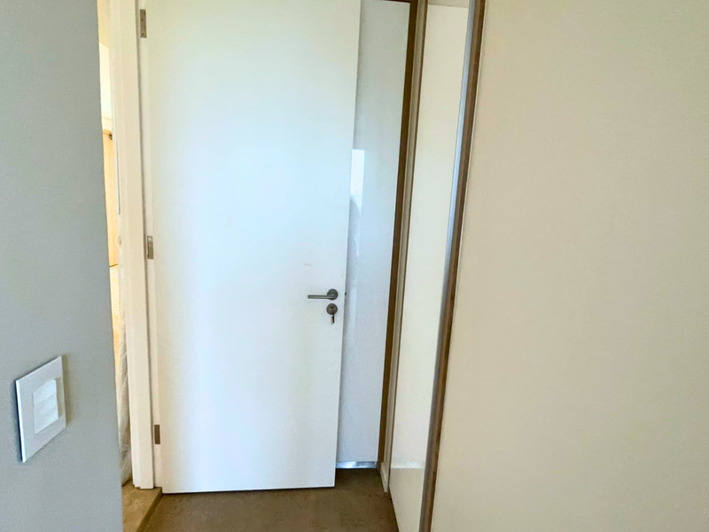 A clean, neutral hallway featuring a built-in cupboard with sliding doors and a standard internal door.