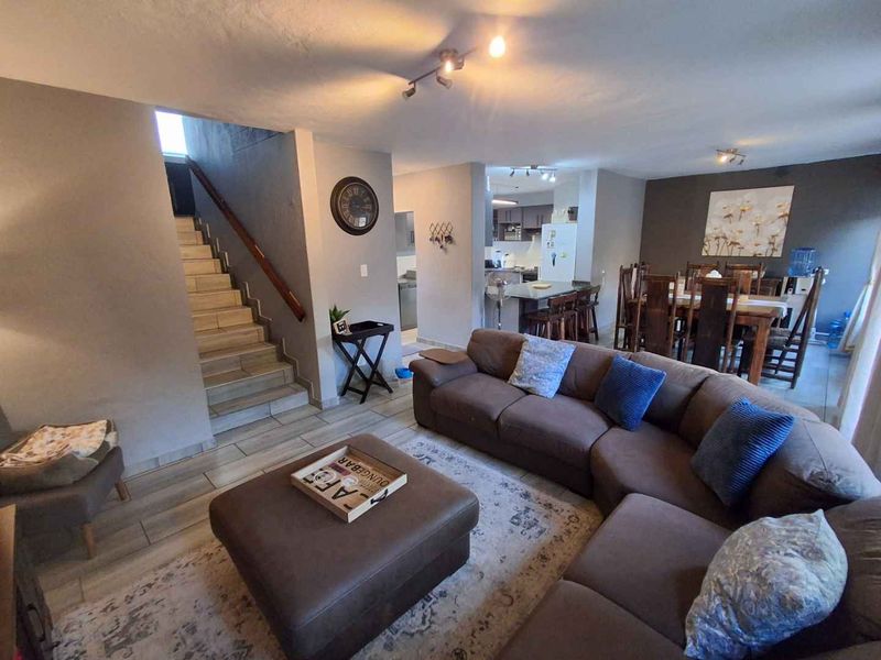 Spacious open-plan living area featuring a tiled staircase, integrated kitchen with island, and neutral finishes throughout, creating a functional and connected home layout.