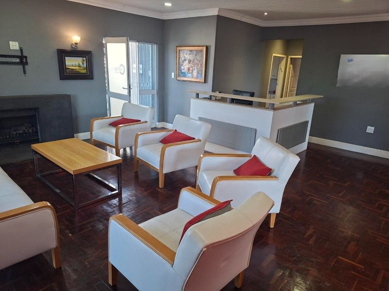 A spacious living area featuring dark parquet flooring, a built-in fireplace, and a reception-style counter, suitable for a professional or residential lounge space.