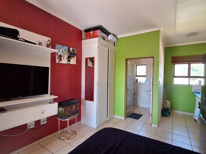 A bedroom featuring tiled flooring, a built-in cupboard, and direct access to an en-suite bathroom.