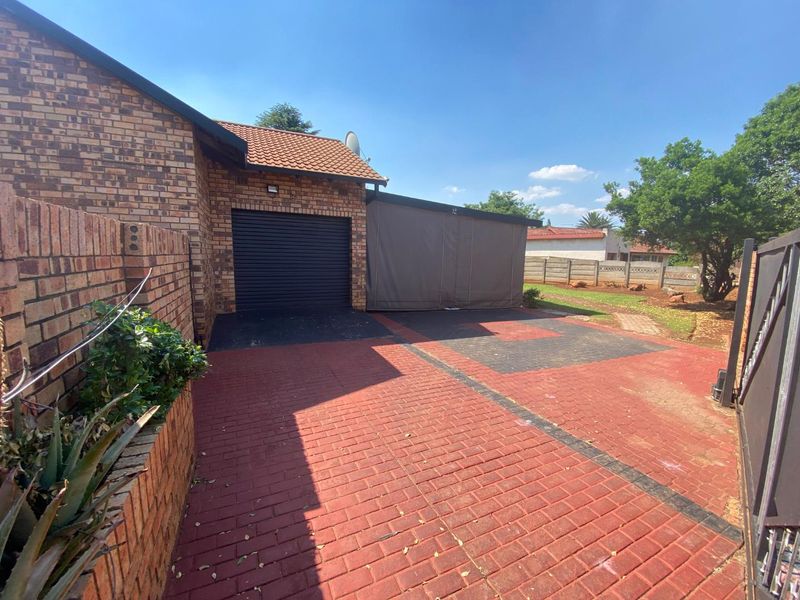 Front exterior view of the property featuring a brick facade, a single garage, a paved driveway, and a covered carport area.