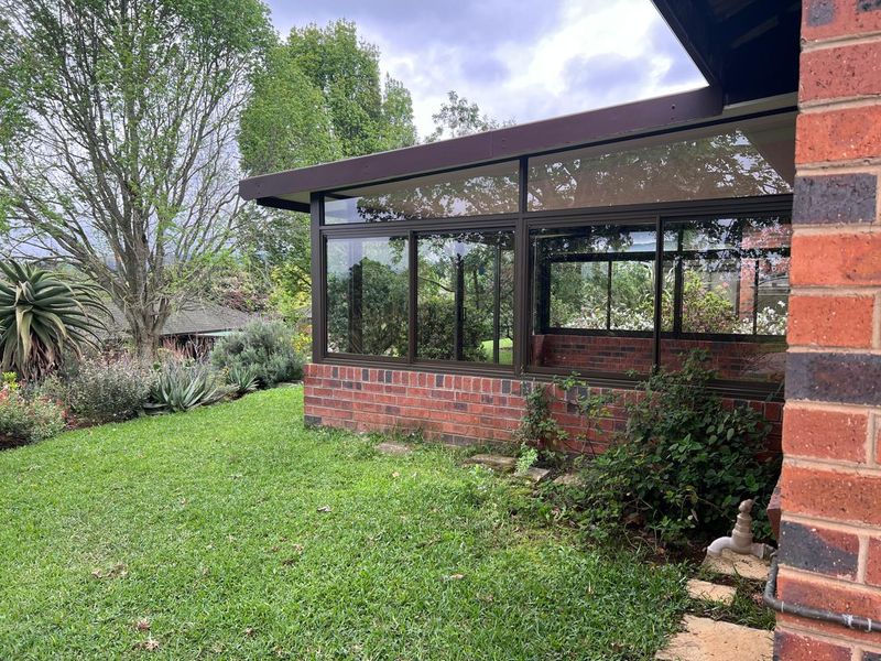 Rear view of the townhouse featuring a brick facade, large sliding glass windows, and a well-maintained garden area.