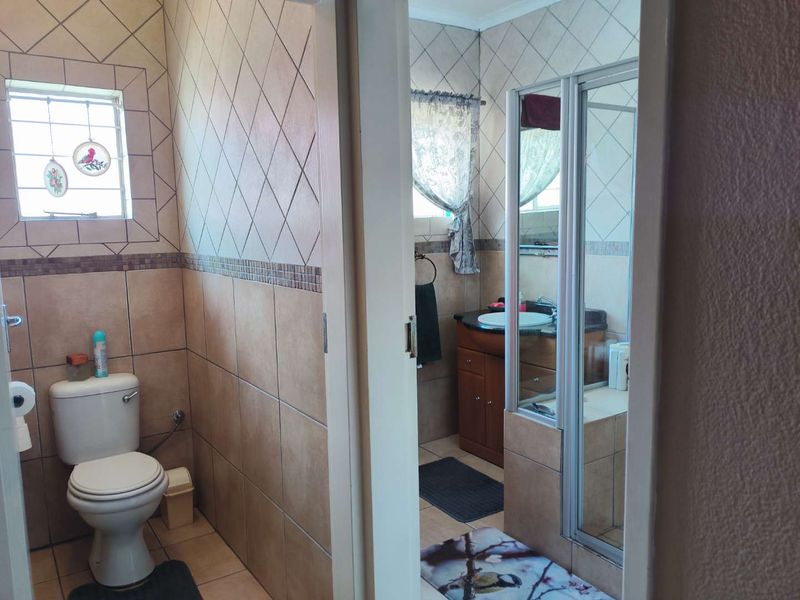A functional bathroom featuring tiled walls, a vanity with basin, and a separate shower enclosure.