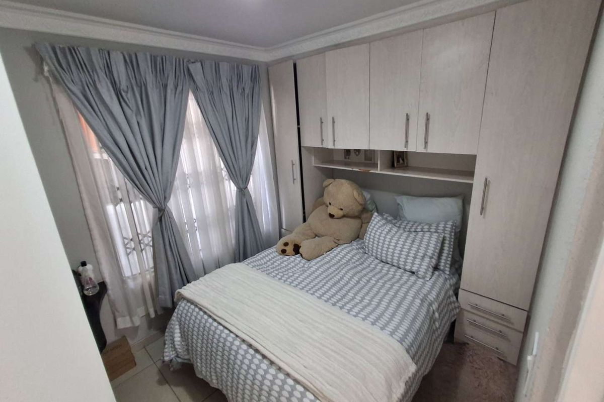 A cozy bedroom featuring light-toned built-in cupboards with overhead storage and tiled flooring.