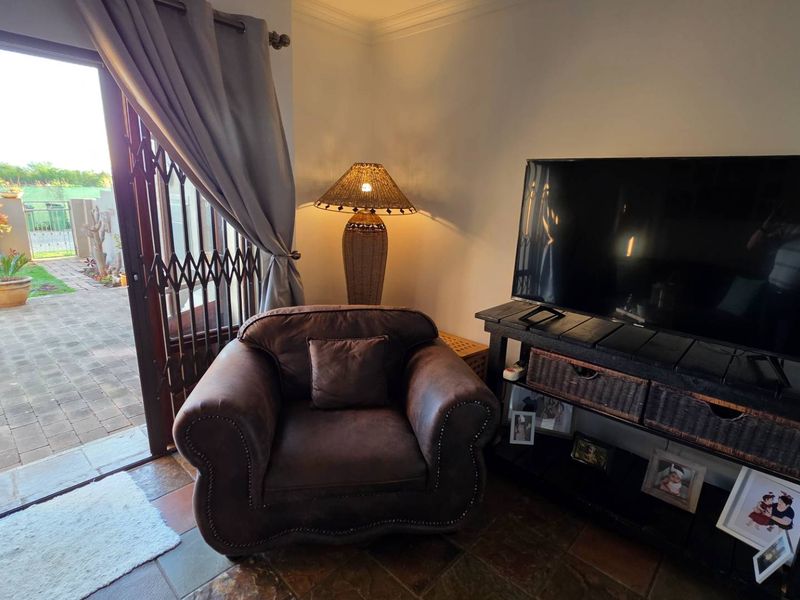 A cozy living area featuring tiled floors and a sliding glass door providing direct access to the outdoor patio and garden.