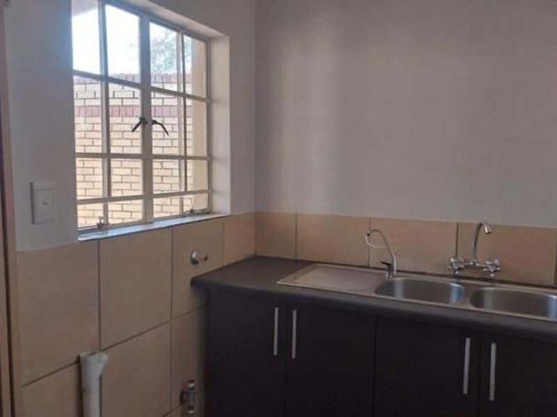 A functional scullery area featuring built-in cabinetry, a double stainless steel sink, and tiled splashbacks, providing a dedicated space for food preparation and cleaning.