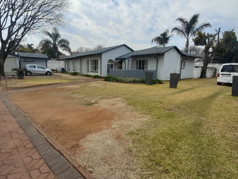 Front view of a single-story residential property featuring a tiled roof, paved driveway, and a detached garage with a surrounding garden area.