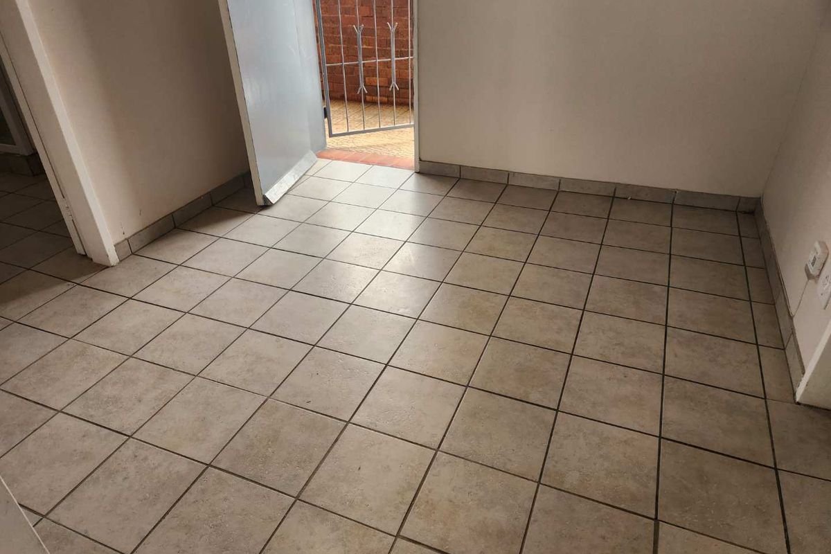 An empty, tiled living area featuring direct access to an outdoor space through a single door.