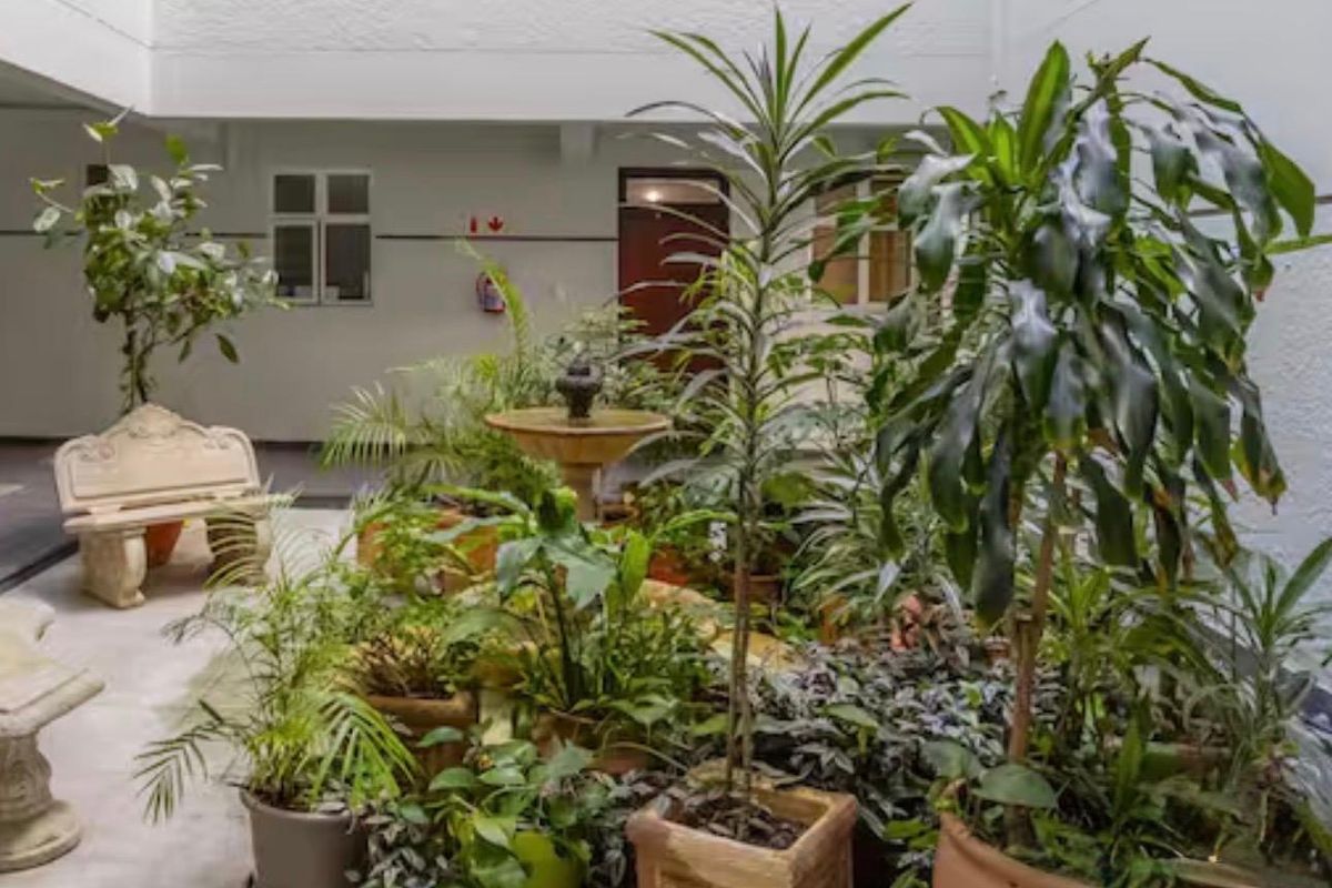 A quiet, paved courtyard area featuring a central stone fountain and surrounding greenery, providing a peaceful outdoor space within the apartment complex.