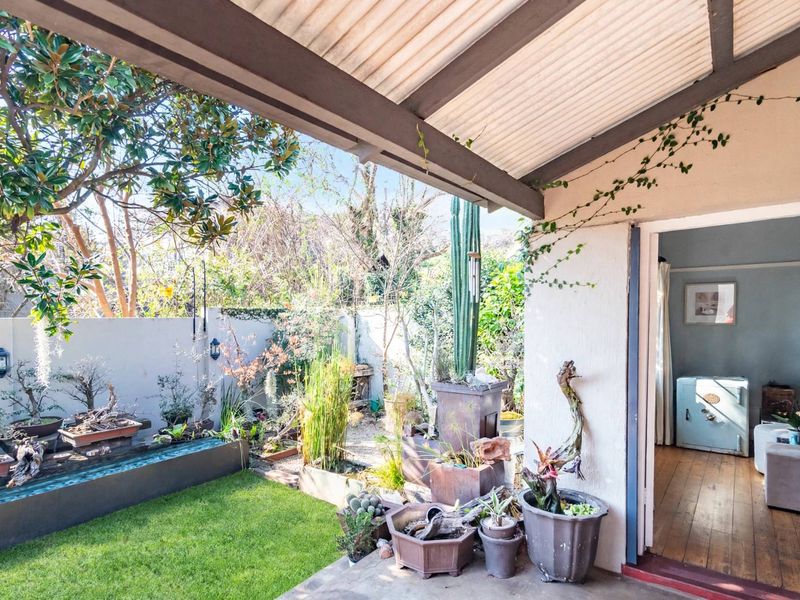 A covered patio area featuring a built-in water feature, concrete flooring, and direct access to a landscaped garden space.