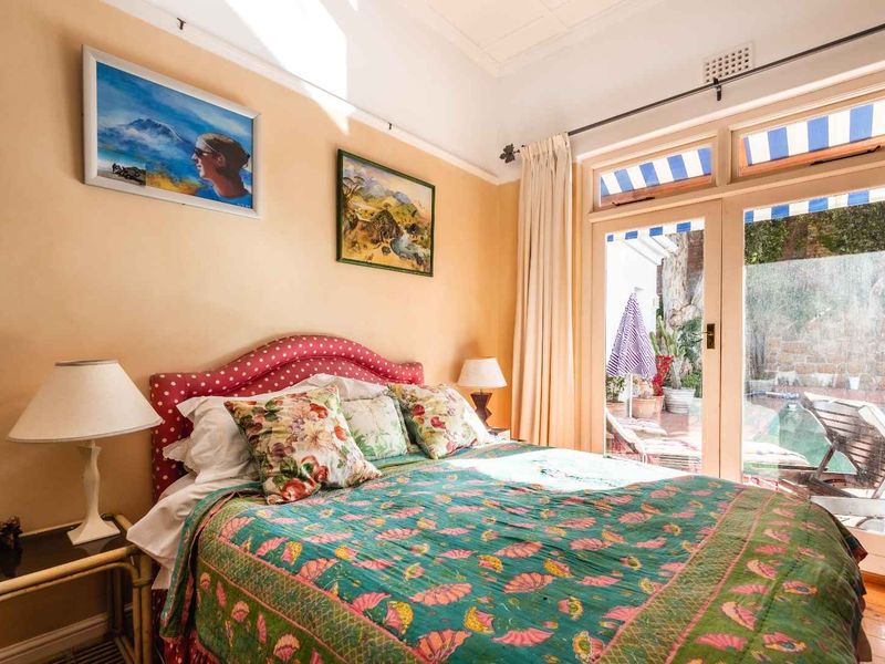 A bedroom featuring timber flooring and classic french doors that provide direct access to the outdoor pool area.
