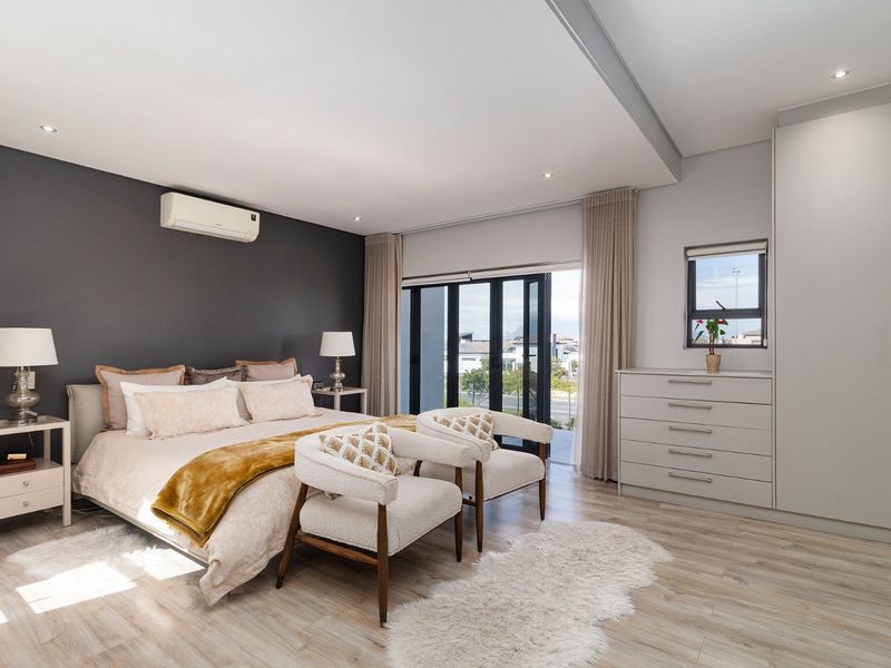 Spacious modern bedroom featuring laminate flooring, built-in cupboards, recessed lighting, a split-system air conditioner, and sliding doors leading to an outdoor area.
