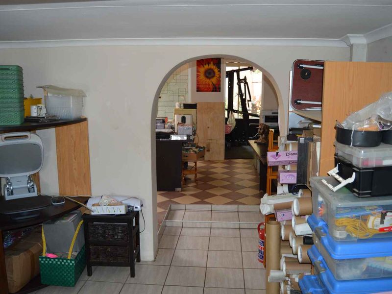 A multi-purpose living area featuring a distinctive arched doorway, tiled flooring, and a brick feature wall, currently used for storage and utility purposes.
