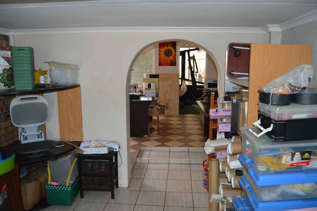 A multi-purpose living area featuring a distinctive arched doorway, tiled flooring, and a brick feature wall, currently used for storage and utility purposes.