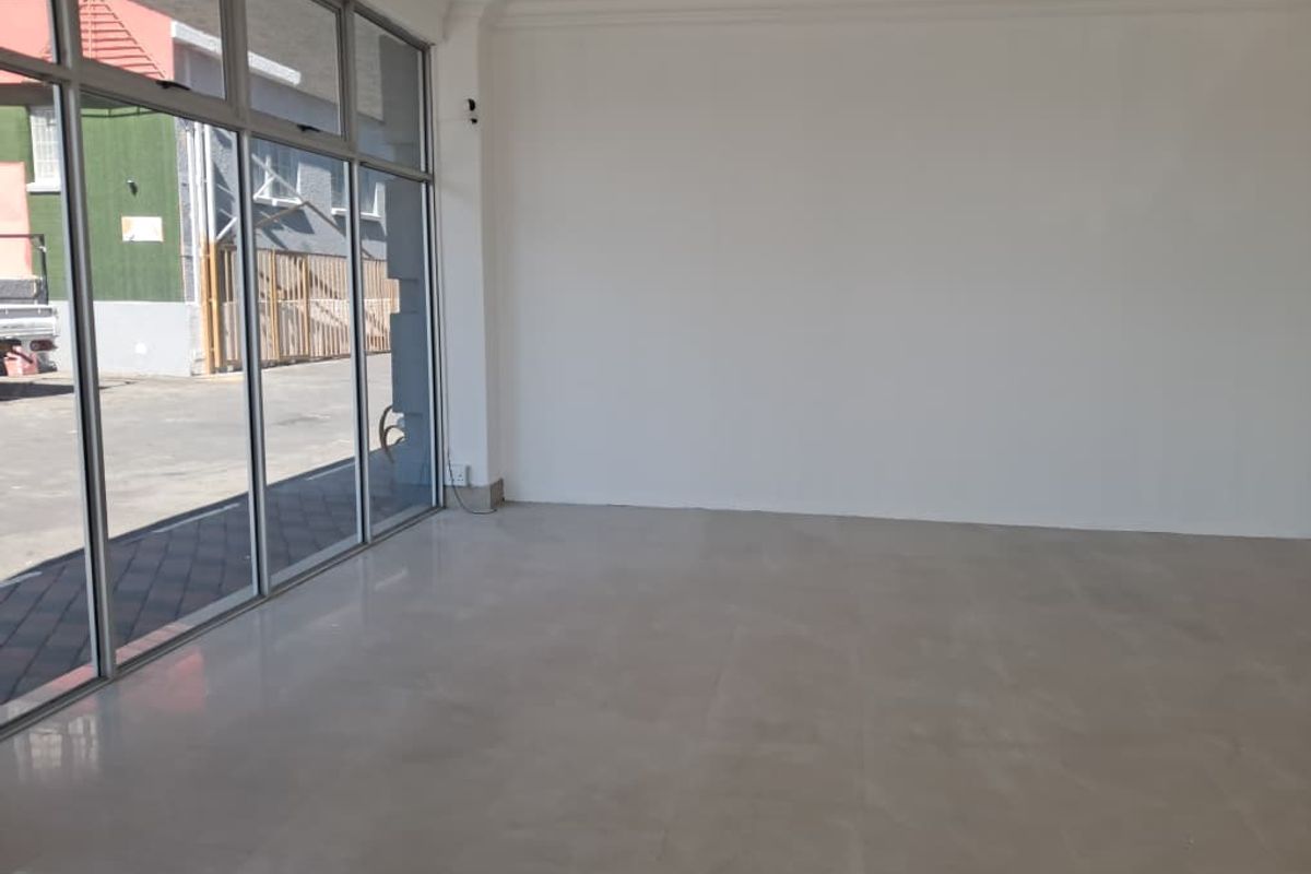 A bright, vacant open-plan retail space featuring large glass storefront windows and clean tiled flooring, suitable for various commercial business applications.