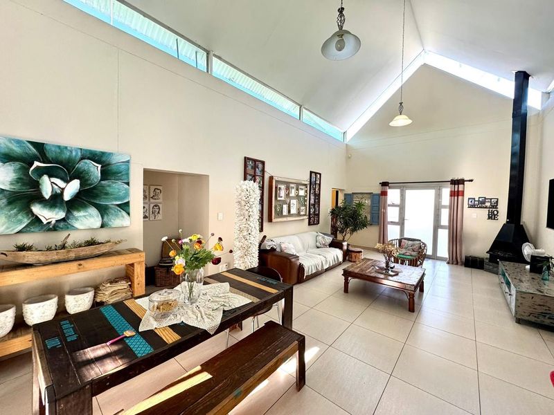 Spacious open-plan living area featuring a high vaulted ceiling with clerestory windows, tiled flooring, and a prominent freestanding fireplace.