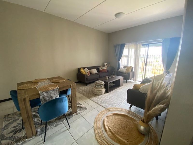 Open-plan living and dining area featuring tiled flooring and a sliding glass door leading to an outdoor space with security gate.