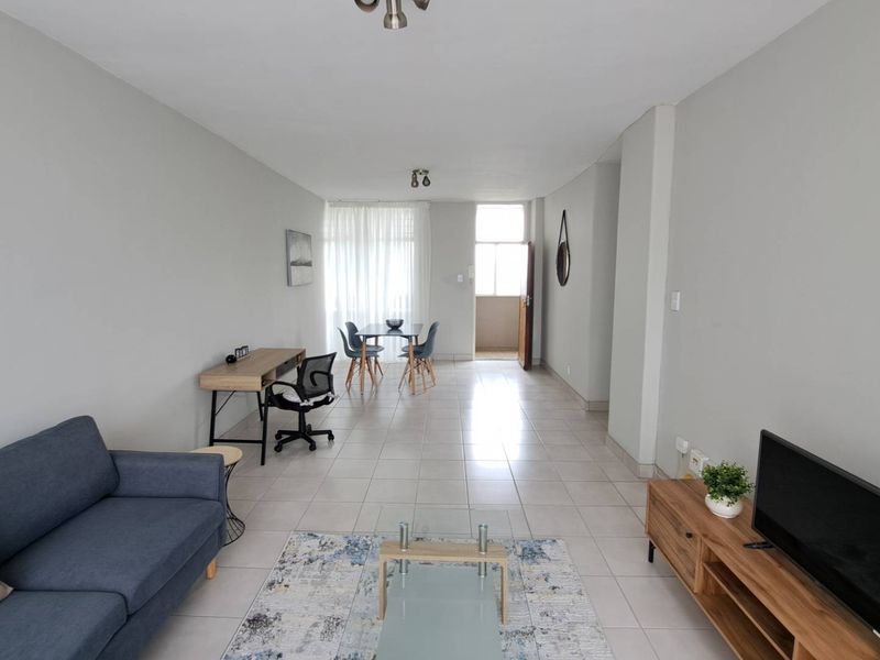 Spacious open-plan living and dining area featuring neutral wall tones, tiled flooring, and direct access to an outdoor balcony.