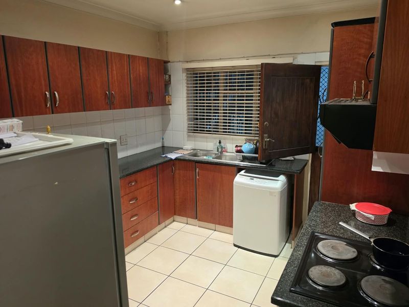 A functional kitchen featuring laminate cabinetry, granite countertops, a double bowl sink, and an electric hob with an extractor fan.