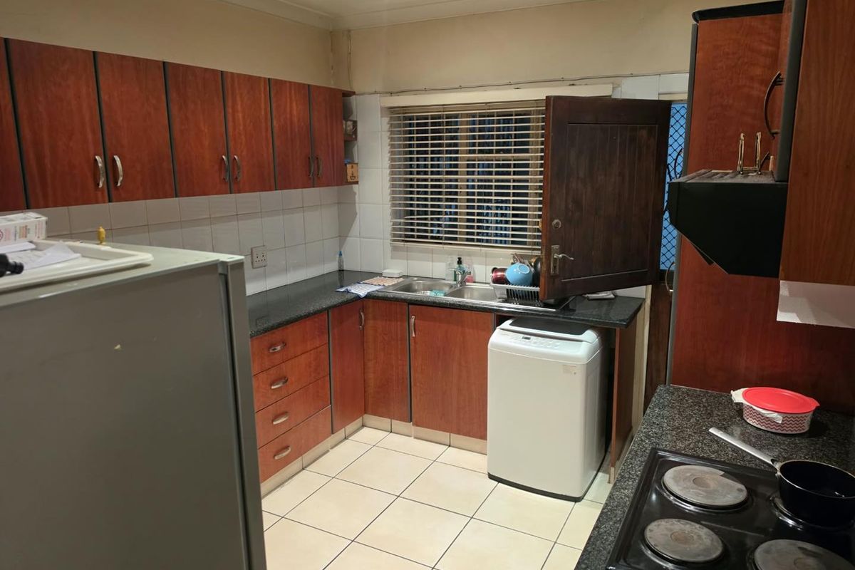 A functional kitchen featuring laminate cabinetry, granite countertops, a double bowl sink, and an electric hob with an extractor fan.