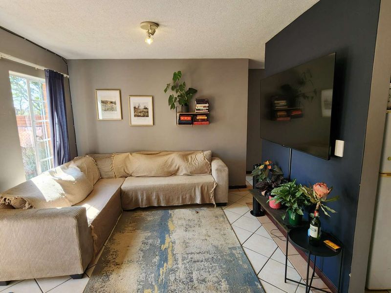 Open plan living area featuring tiled flooring and a dark accent wall, providing a functional space adjacent to the kitchen area.