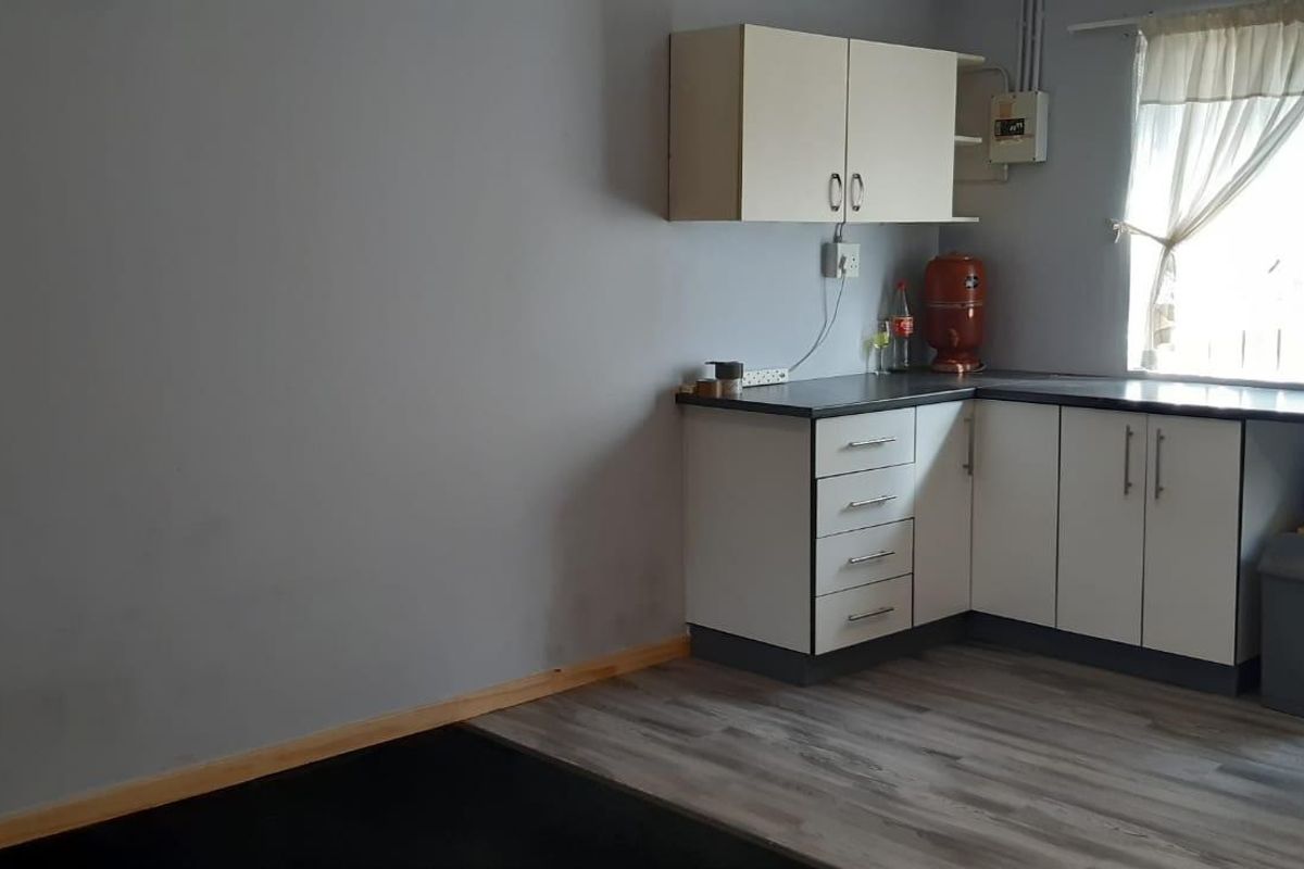 A compact kitchen area featuring laminate cabinetry, countertops, and wood-look flooring, providing a functional space with basic storage and preparation surfaces.