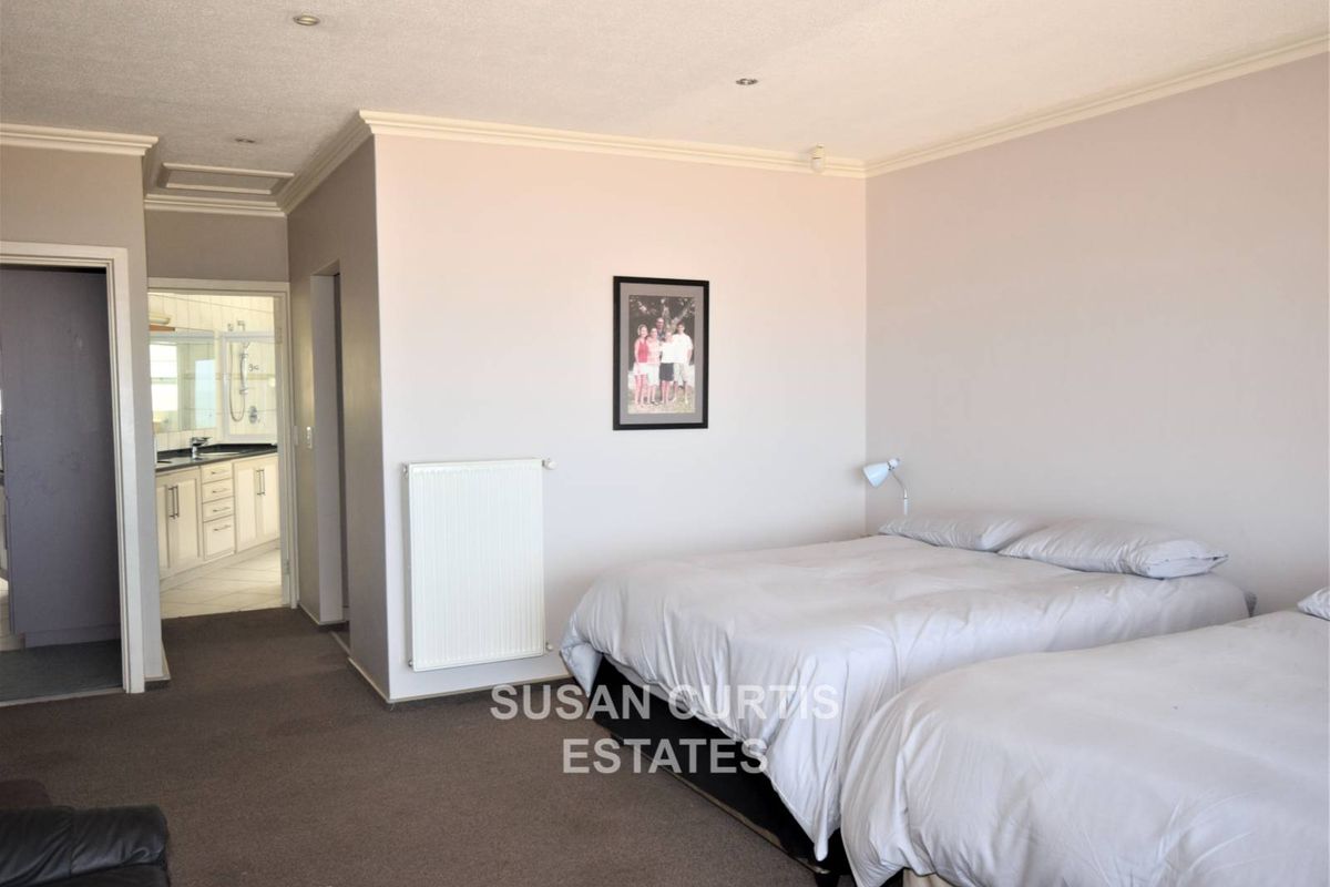 Spacious bedroom featuring neutral walls, recessed ceiling lighting, and an attached en-suite bathroom with vanity and shower.