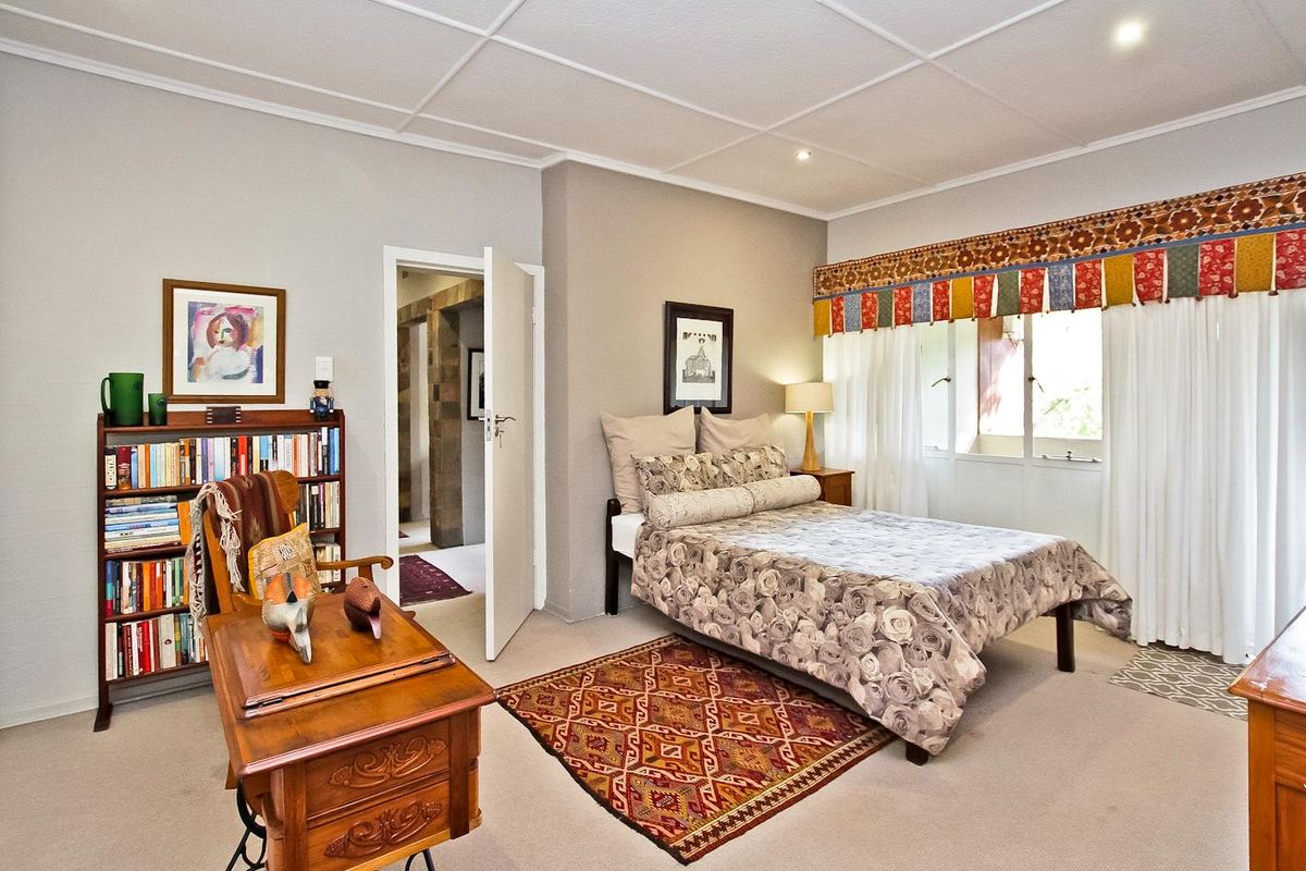 A well-lit bedroom featuring neutral wall tones, carpeted flooring, and a classic ceiling design, providing a comfortable and functional living space.