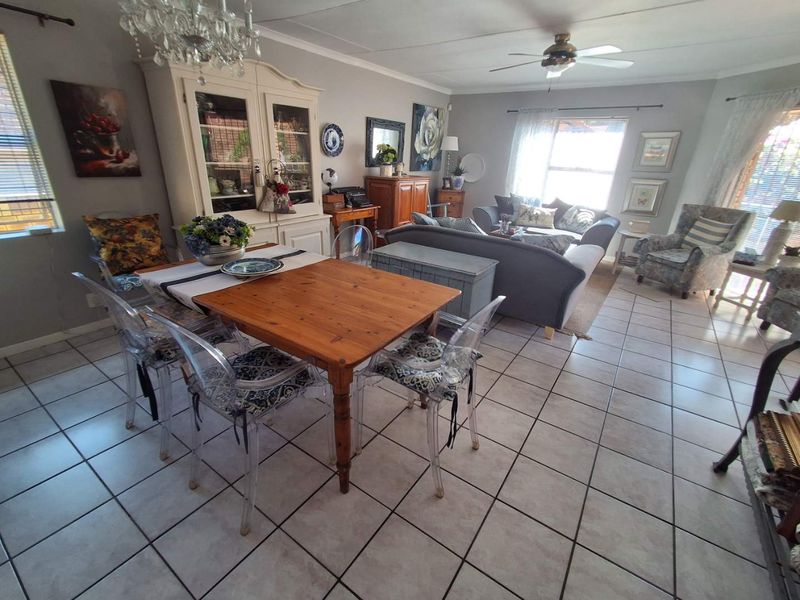 Spacious open-plan living and dining area featuring neutral tiled flooring, a ceiling fan, and a decorative chandelier, offering a versatile layout for family living.