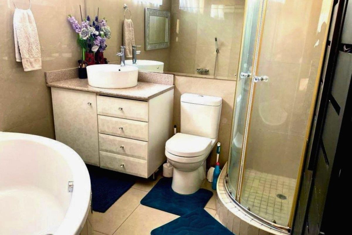 A functional bathroom featuring a corner shower enclosure, a freestanding circular bathtub, and a vanity unit with a vessel sink.