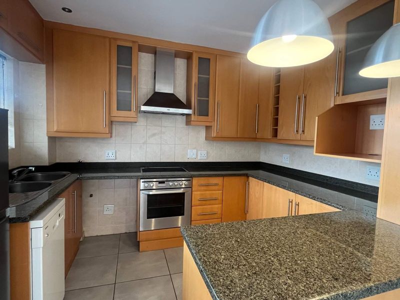 Functional kitchen featuring light wood cabinetry, granite countertops, tiled splashbacks, and integrated stainless steel appliances.