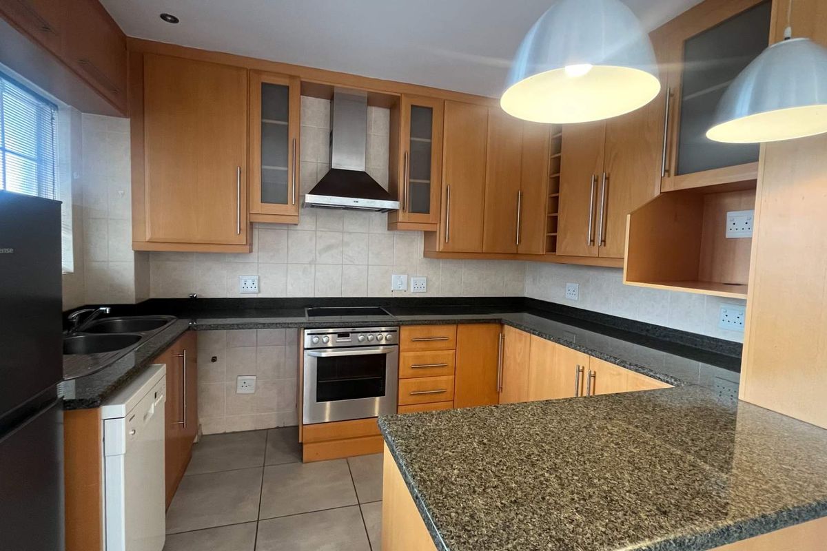 Functional kitchen featuring light wood cabinetry, granite countertops, tiled splashbacks, and integrated stainless steel appliances.