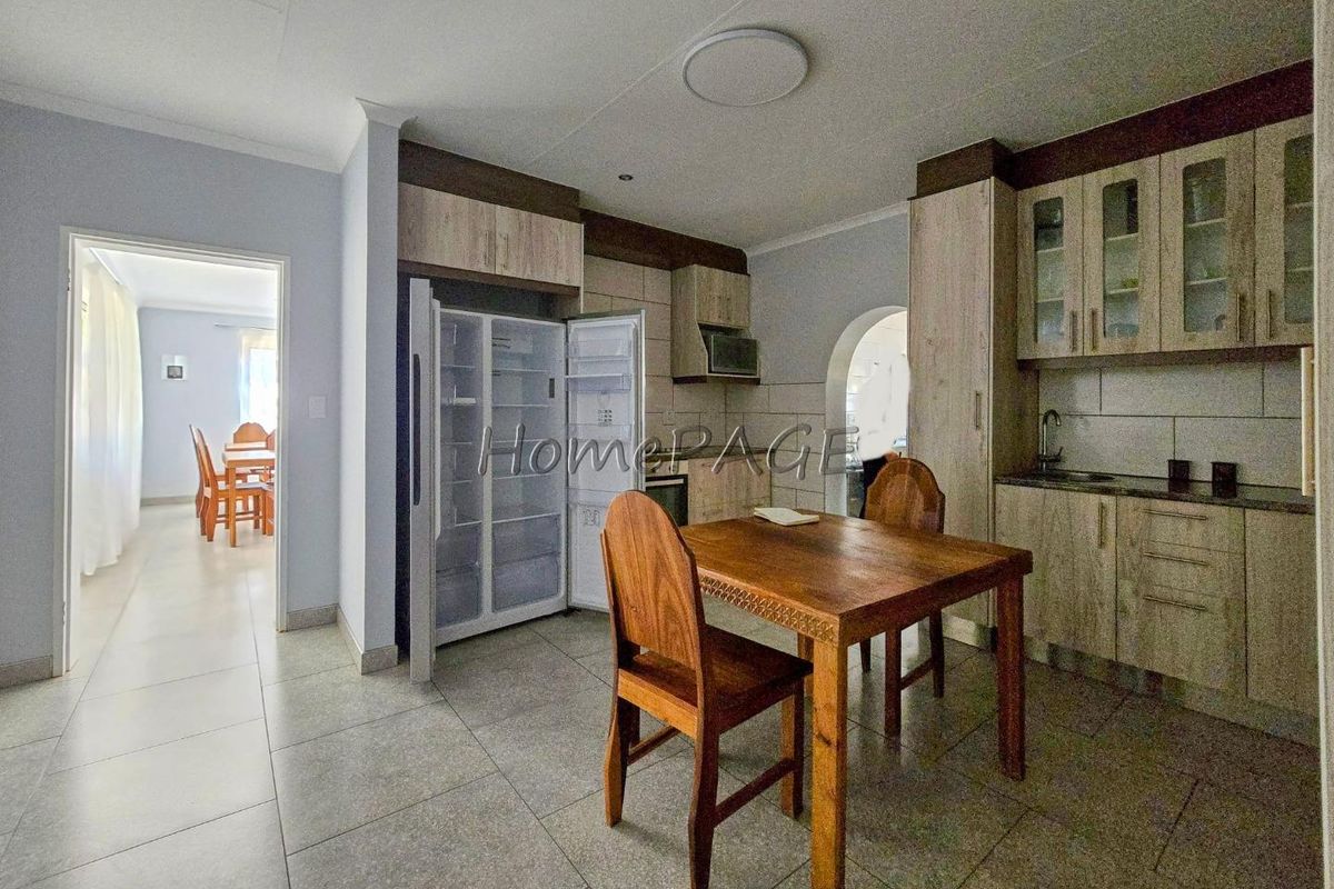 A functional kitchen featuring built-in cabinetry, tiled flooring, and integrated appliances, with an open-plan layout leading to the dining area.