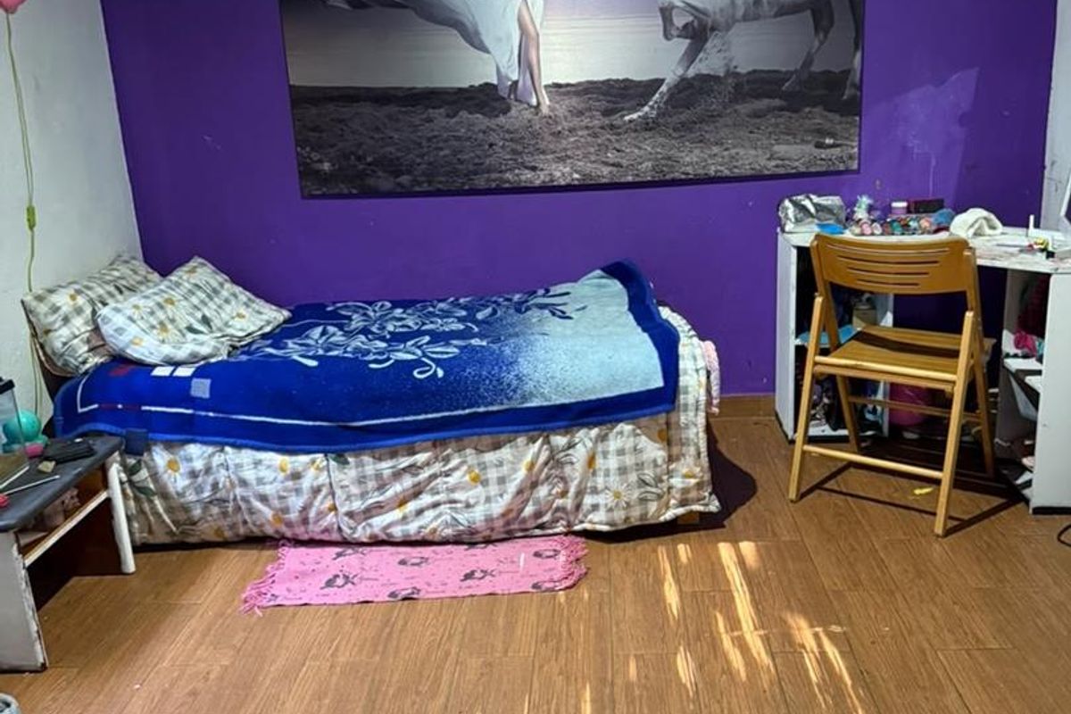 A bedroom featuring wood-look tile flooring and an exposed timber ceiling beam, currently finished with a bold purple accent wall.
