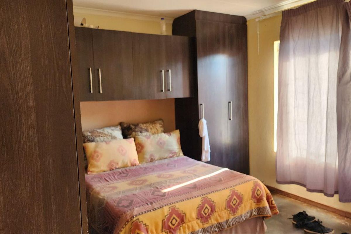 A bedroom featuring built-in dark wood cabinetry and overhead storage units, providing functional storage space with natural light from the window.