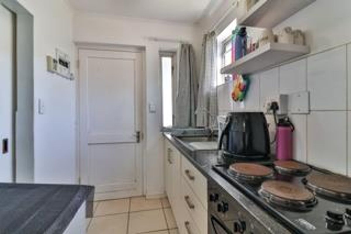 Compact kitchen featuring built-in cabinetry, a four-plate electric hob, and tiled splashbacks, providing a functional workspace.