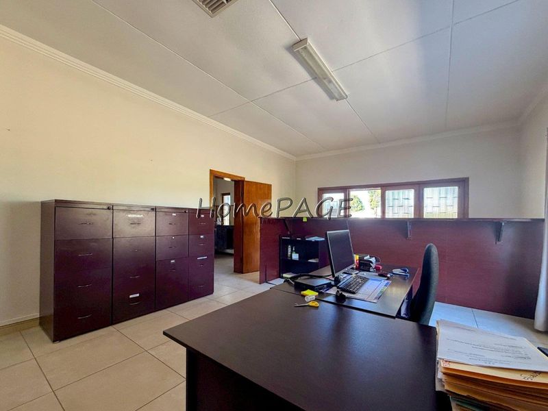 A functional office space featuring tiled flooring, timber window frames with security bars, and a built-in timber partition wall.